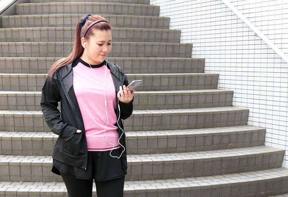スポーツウェアのモデル着用イメージ(スマホで音楽を聴きながらジョギングしようとしているシーン)